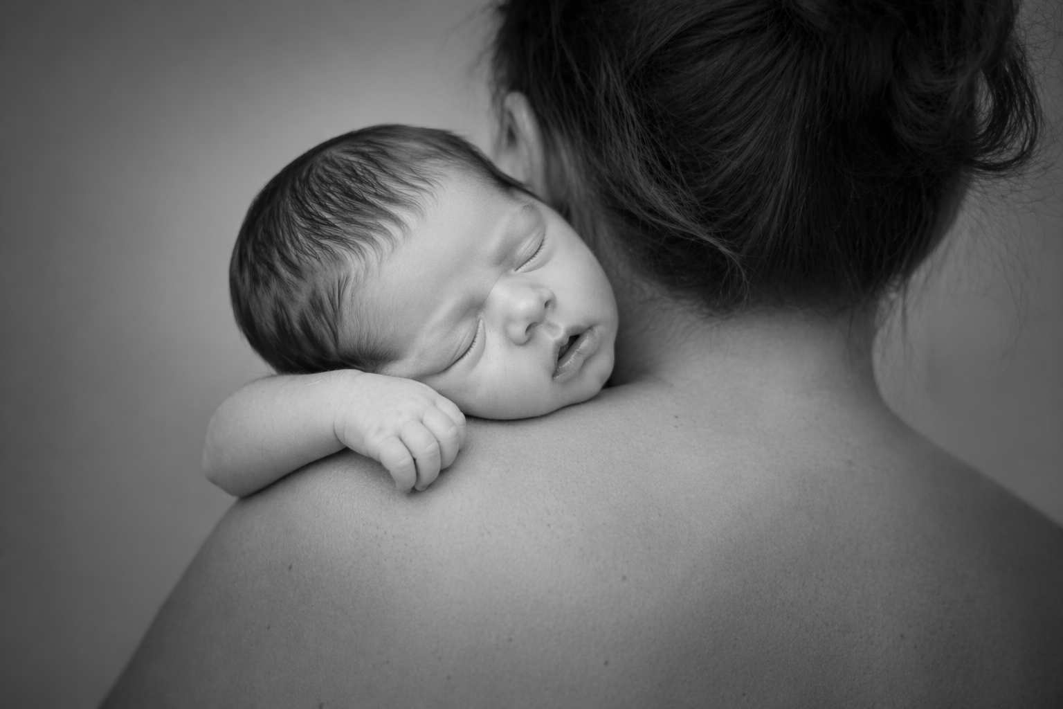 Newborn resting peacefully on a mother’s shoulder photographed by Dolce Vita Doulas.