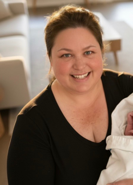 Chandra Redinger smiling while holding a newborn baby.